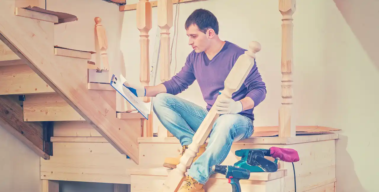 Instalar peldaños de madera en escaleras. Hombre sentado en escalera de madera con herramientas